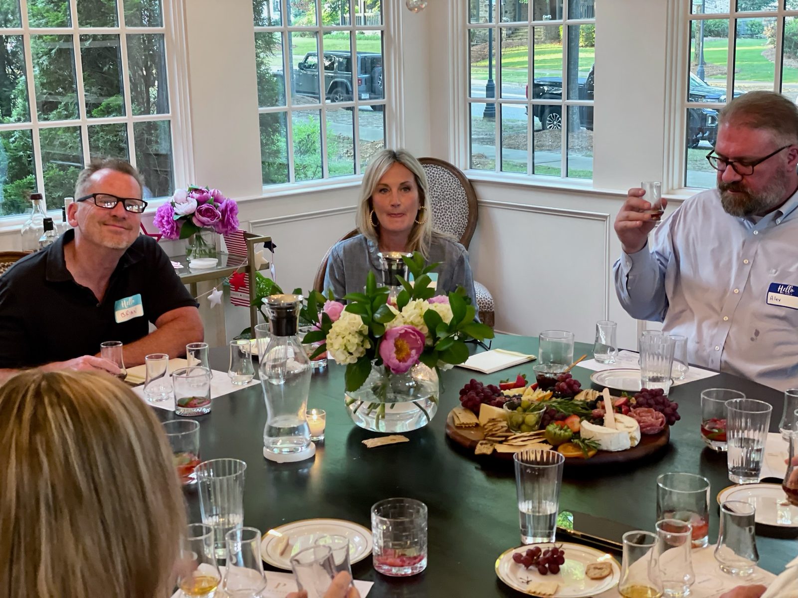 Three guests at a tasting table, one raising a glass.